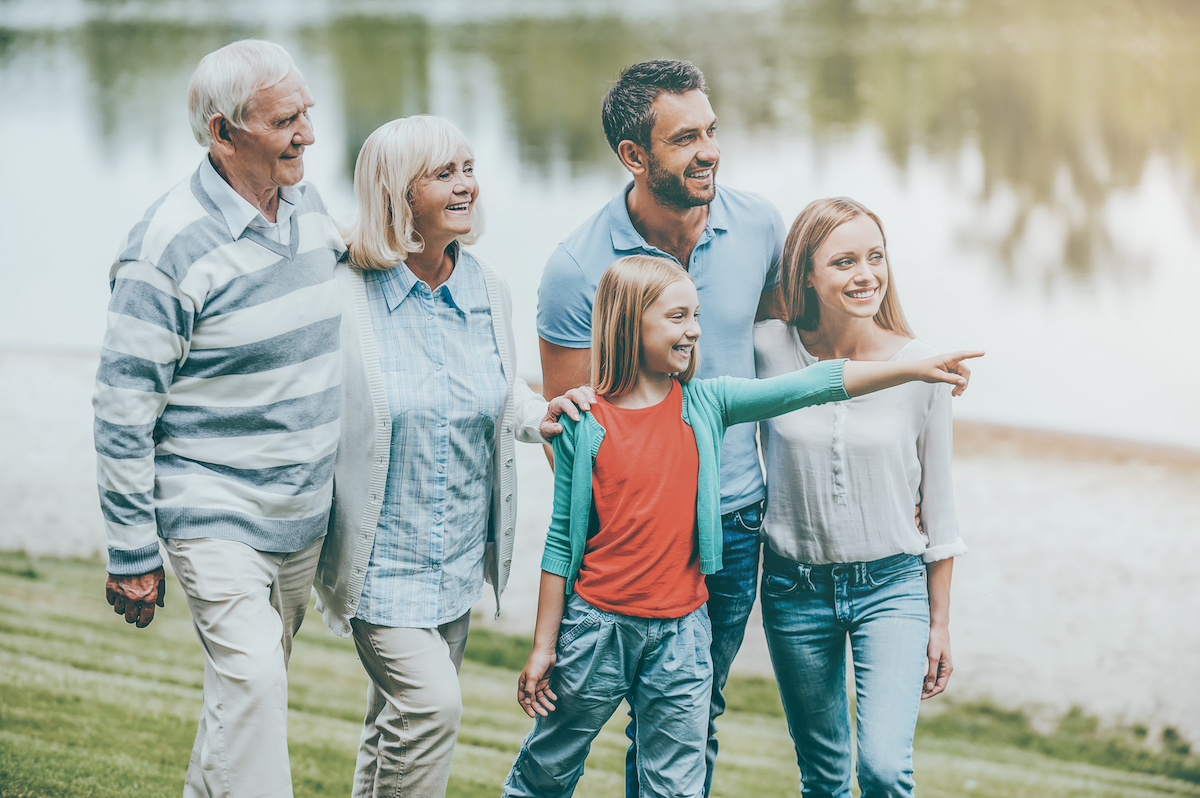 Family time. Happy young family walking outdoors together while little girl pointing away and smiling